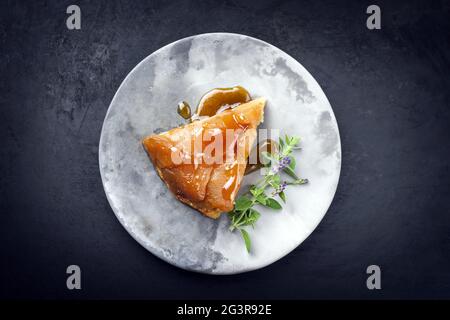 Tradizionale tatin francese con mele e vaniglia offerto come vista dall'alto su un design moderno piatto con sfondo rustico con Foto Stock