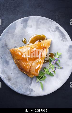 Tradizionale tatin francese con mele e vaniglia offerto come vista dall'alto su un design moderno piatto con sfondo rustico con Foto Stock