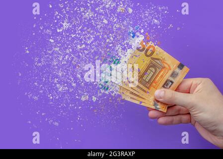 inflazione euro . Inflazione in Europa, iperinflazione. Banner con sfondo viola. Cinquanta banconote in euro spruzzate in mano a un uomo su una ba viola Foto Stock