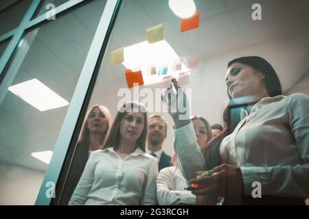 Le ragazze degli impiegati dell'ufficio incollano le note sugli adesivi sulla finestra dell'ufficio. Incontro al lavoro. Foto di alta qualità Foto Stock