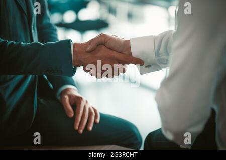 I dipendenti si stringono le mani durante una riunione aziendale. Fare un accordo tra i partner. Due uomini in tute. Foto di alta qualità Foto Stock