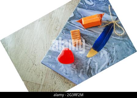 caramelle dolci colorate con piuma su carta ondulata marmorizzata, espressione tema amore, gelatina forma cuore, spazio di testo carta da parati sentimenti Foto Stock