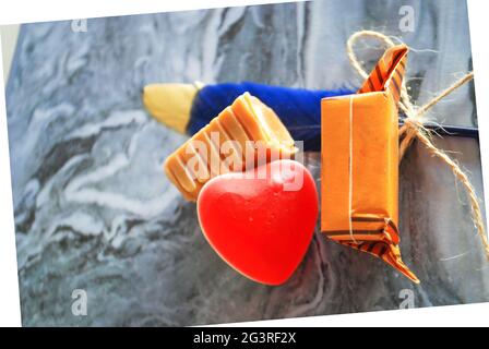 caramelle dolci decorative con piuma blu sfocata su carta ondulata marmorizzata morbida messa a fuoco, tema d'amore che esprime la carta dei sentimenti, gelatina forma del cuore, Foto Stock