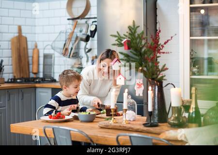 Madre con figlio in cucina durante le vacanze di Natale Foto Stock