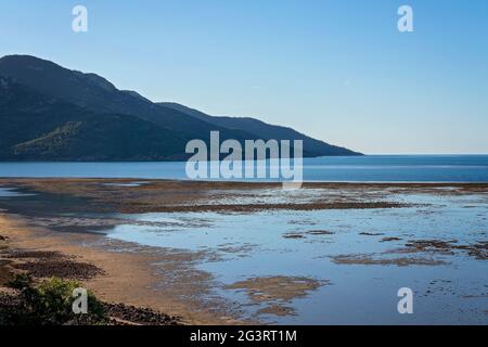 Vista dalla cima di una collina che si affaccia sul Mar dei Coralli con la bassa marea sotto un cielo blu chiaro Foto Stock