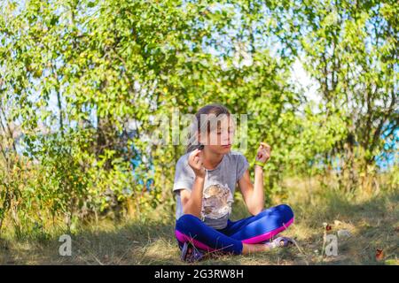 Defocus caucasica presteen ragazza praticante yoga in parco, foresta, all'aperto, all'aperto. Meditazione e concentrazione. Benessere stile di vita sano. Yoga ragazza. Foto Stock