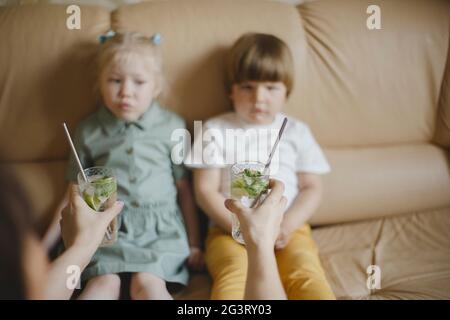 Donna che tiene fuori i cocktail con le padelle riutilizzabili ai bambini Foto Stock