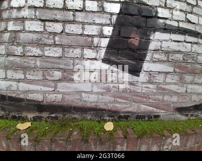 graffiti: Martello nero su muro bianco di mattoni sopra muschio, colpo di martello sulla natura / contro la natura , Germania Foto Stock