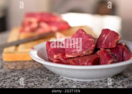 Carni rosse fresche a dadini in un piatto profondo. Primo piano. Foto Stock