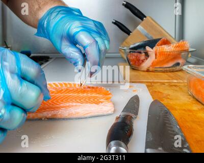 Rimozione delle pinzette dai filetti di salmone durante il taglio del pesce. Foto Stock