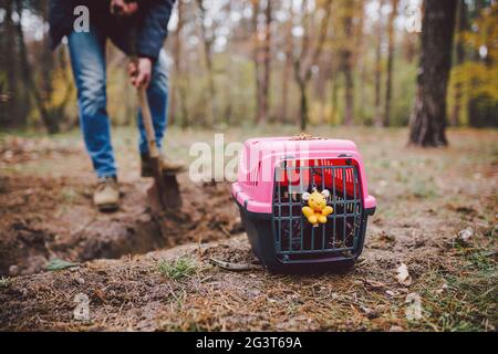 Scena Spooky al cimitero degli animali domestici. La tomba di amici animali perduti. Compagnia, addio. Un uomo porta un animale domestico morto in una carrie Foto Stock