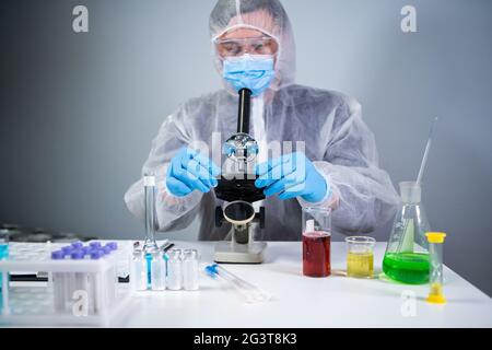 I produttori farmaceutici sviluppano farmaci virali inventando l'ingrediente migliore. Lo scienziato indossa dispositivi di protezione personale Foto Stock