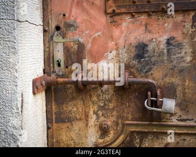 Lucchetto arrugginito su una vecchia porta di metallo Foto Stock