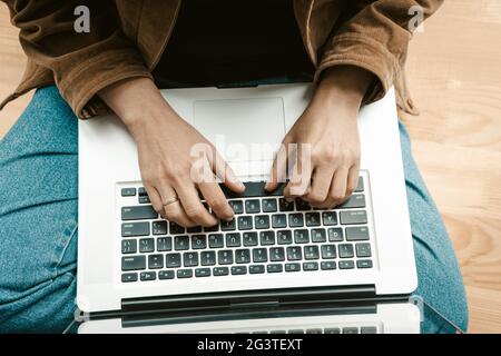 Primo piano. Vista dall'alto. Le mani della donna lavorano con un computer portatile seduto su un davanzale. Bella donna anziana gestisce i propri affari Foto Stock