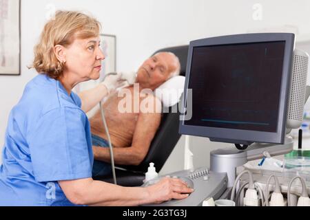 Tecnico femminile diagnosi paziente maschio utilizzando i moderni scanner ad ultrasuoni in clinica privata Foto Stock