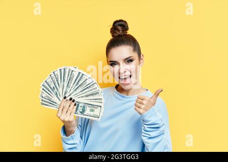 Felice giovane donna eccitato mostrando banconote di denaro con pollici in su Foto Stock