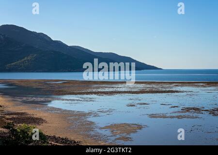 Vista dalla cima di una collina che si affaccia sul Mar dei Coralli con la bassa marea sotto un cielo blu chiaro Foto Stock