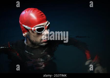 Un autentico nuotatore triatleta che fa una pausa durante un allenamento duro di notte Foto Stock