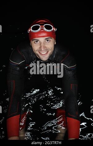 Un autentico nuotatore triatleta che fa una pausa durante un allenamento duro di notte Foto Stock