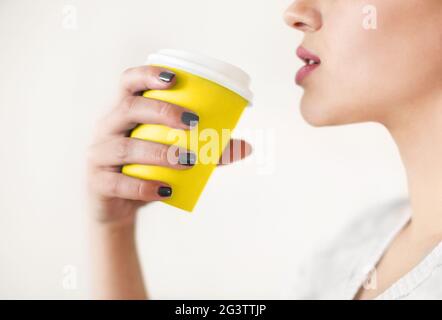 Donna con illuminante tazza gialla di caffè seduto al tavolo Foto Stock