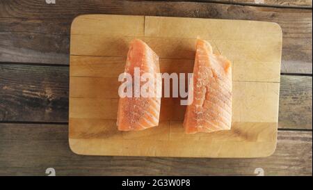 Due filetti di salmone crudo su tagliere di legno Foto Stock