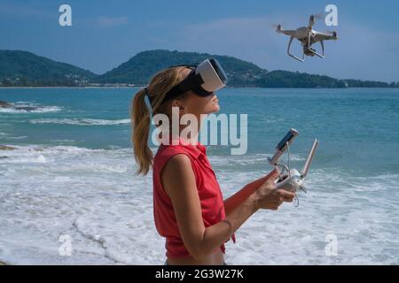 Woan con fotocamera drone e occhiali di realtà virtuale che scattano foto e video sulla spiaggia Foto Stock