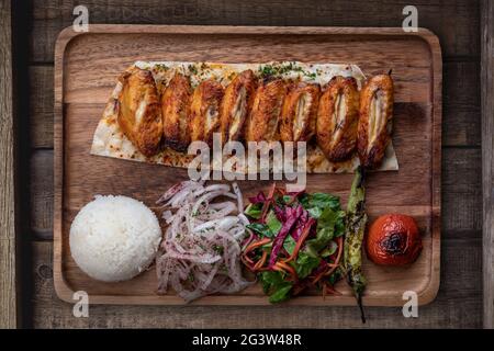Ali di pollo turche kebab con riso e verdure su rustico tavolo di legno Foto Stock