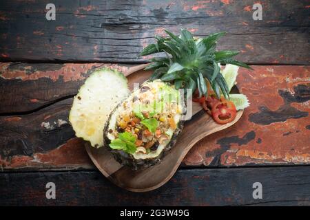 Vista dall'alto cibo tailandese ananas pollo riso fritto su rustico tavolo di legno Foto Stock