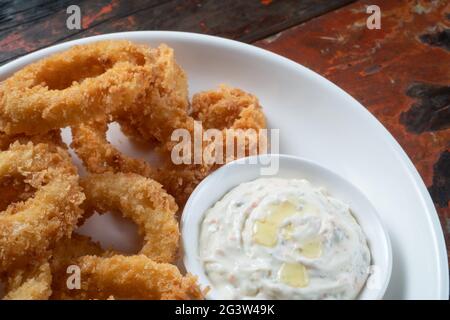 Anelli di calamari fritti con salsa di immersione isolata su rustico tavolo di legno Foto Stock