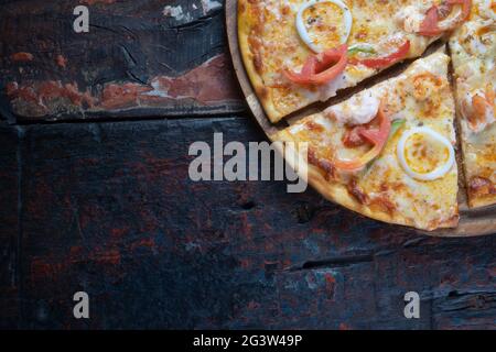 Pizza fresca e gustosa con frutti di mare, pomodoro, paprika e mozzarella su rustico fondo di legno Foto Stock