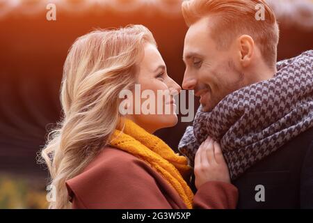 Super primo piano di baciare la giovane coppia. Marito e una moglie hanno abbracciato il sorriso guardarsi l'un l'altro nel parco autunnale. Scatto all'aperto o Foto Stock