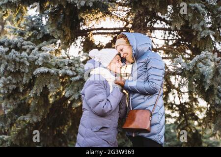 Concetto di famiglia felice, vecchiaia, emozioni, assistenza senior in età pensionabile. Nonna anziana attiva e figlia adulta abbracciano Foto Stock