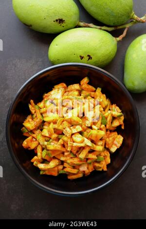 Insalata di mango verde. Crude mango Instant pickle. Conosciuto anche come kairichi koshimbir in Marathi. Copia spazio su sfondo nero. Mangos verdi tritati crudi. Foto Stock