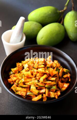 Insalata di mango verde. Crude mango Instant pickle. Conosciuto anche come kairichi koshimbir in Marathi. Copia spazio su sfondo nero. Mangos verdi tritati crudi. Foto Stock