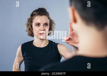 Allenatore insegna all'atleta a colpire il calcio. Forti atleti di arti marziali femminili nella loro formazione taekwon-do. Due giovani donne istruttore Foto Stock