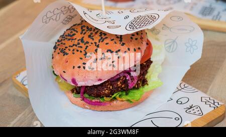 Foto ravvicinata di un hamburger vegetariano con una patina di barbabietole in un panino di sesamo Foto Stock