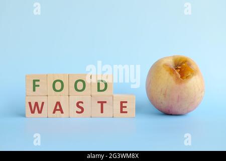 Concetto di spreco di cibo. Rottami di frutta e verdura con blocchi di legno tipografia su sfondo blu con spazio di copia. Foto Stock