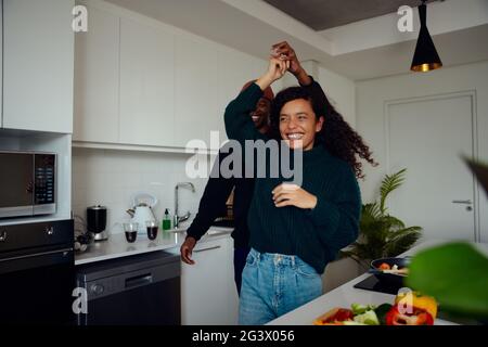 Misto gara coppia divertirsi in cucina. Una coppia mista che danzano insieme. Foto di alta qualità Foto Stock