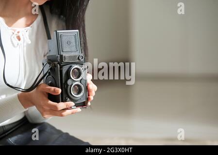 Primo piano di una donna irriconoscibile che utilizza una fotocamera d'epoca mentre fotografa in studio Foto Stock