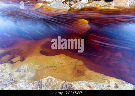 Una vista astratta di un letto di fiume in una miniera abbandonata area con depositi di minerali e metalli in acque poco profonde Foto Stock