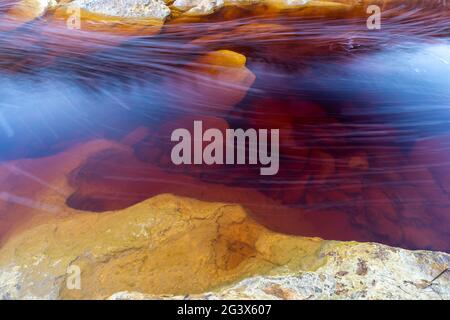 Vista astratta di un letto di un fiume in un'area mineraria abbandonata con depositi di minerali e metalli in acque poco profonde Foto Stock