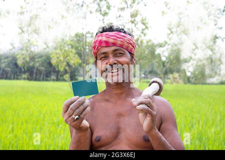 Contadino indiano rurale che mostra la carta Business in campo agricolo Foto Stock