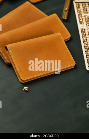 Accessori in pelle fatti a mano, abbinati in un colore, moda, governante, portafoglio, porta carte di credito senape giallo su sfondo verde Foto Stock