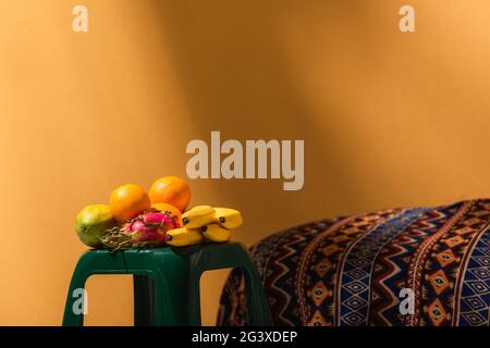 frutta esotica su sgabello vicino coperta ornamentale su arancione Foto Stock