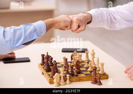 Due uomini d'affari che giocano a scacchi in ufficio Foto Stock