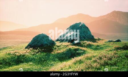 Prato con enormi pietre tra l'erba sulla collina al tramonto Foto Stock