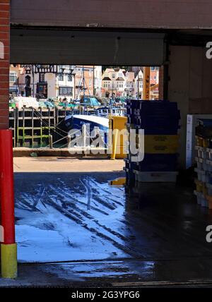 Guardando attraverso l'edificio dei grossisti di pesce fino al porto di Scarborough. Una parte della flotta peschereccia è ormeggiata dopo lo sbarco delle catture Foto Stock