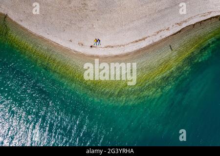 La coppia si trova su una spiaggia, acqua azzurra del lago, l'improbabile paesaggio aereo, Italia, Dolomiti, tempo soleggiato, costa Foto Stock