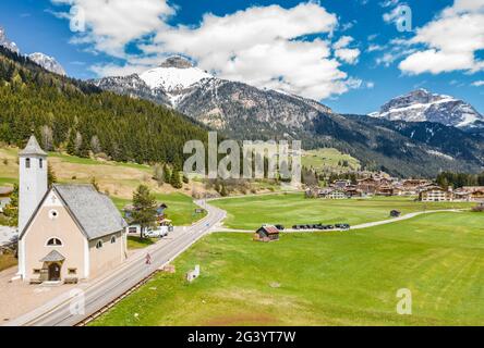 Vista aerea della valle con Chalet, verdi pendii delle montagne d'Italia, Trentino, Fontanazzo, enormi nuvole su una valle, tetto Foto Stock