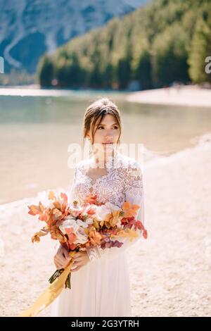 Bella sposa in un abito bianco con maniche e pizzo, con un bouquet giallo autunno di fiori secchi e rose di pony, sulla Los Angeles Foto Stock